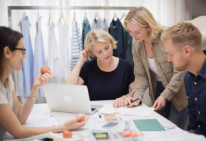 Modedesigners som samarbetar kring klädskisser i en studioworkspace i Stockholm, Sverige.